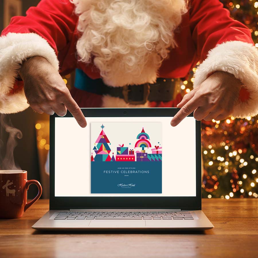 Santa Claus standing behind a desk and pointing Christmas brochure on the laptop screen, Christmas and communication concept