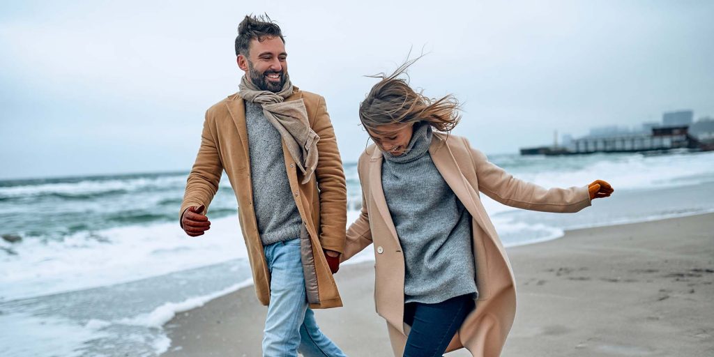 Couple on the beach dressed in coats in the autumn season.