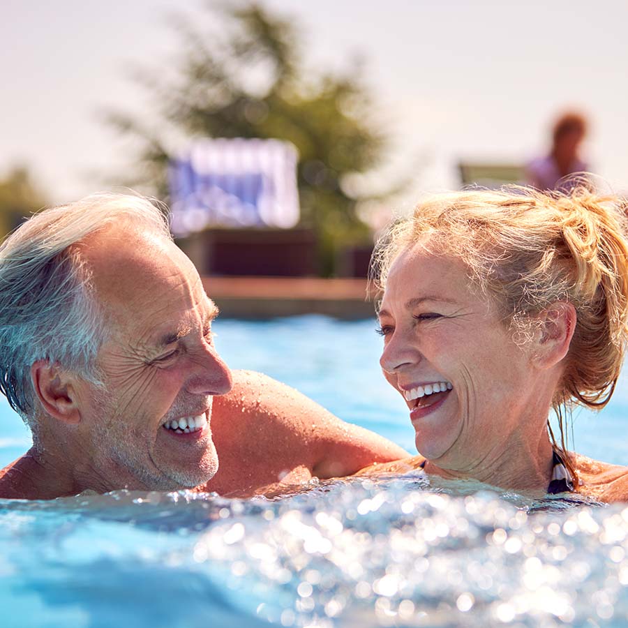 Retired Senior Couple Relaxing In Swimming Pool On Summer Vacation