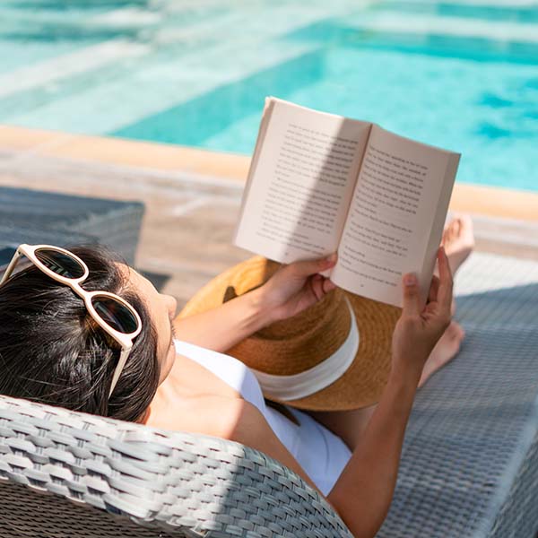 Lady reading a book lying on poolside lounger